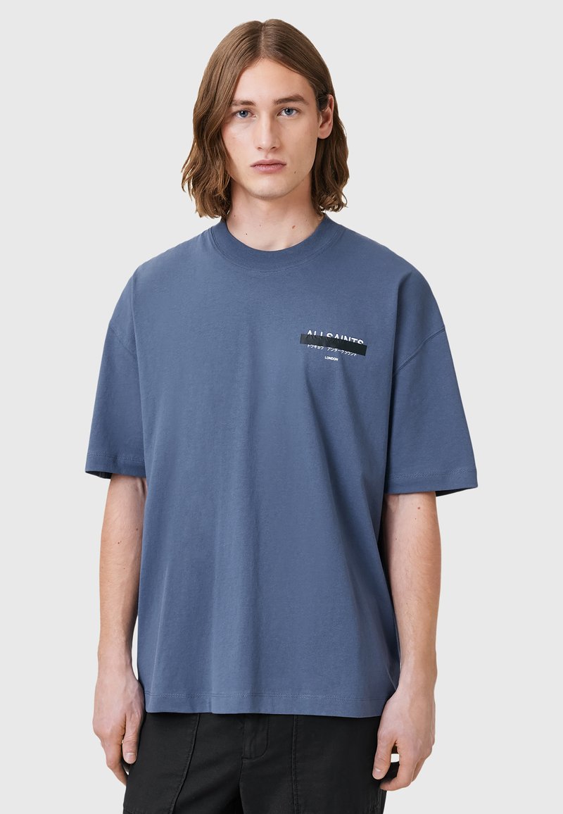 Blå bomulds T-shirt med rund halsudskæring, korte ærmer og et grafisk labeldetalje foran. Har en afslappet pasform og blød tekstur.