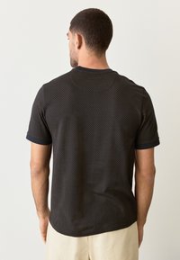 Black short-sleeve shirt with a textured check pattern, contrasting cuffs, subtle sheen, and a relaxed fit.