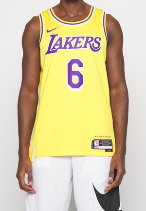 Mężczyzna w żółtej koszulce do koszykówki Los Angeles Lakers z numerem 6 i białych szortach z czarnym logo Nike.