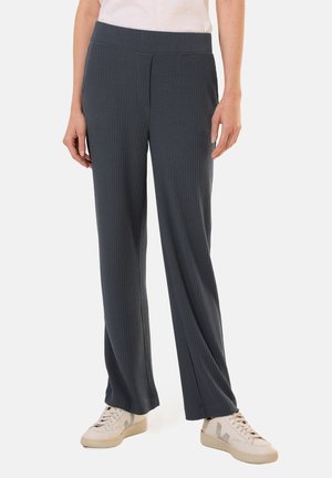 Pantalons larges à côtes gris avec une taille élastique, associés à des baskets blanc cassé. Présentés sur un fond neutre.