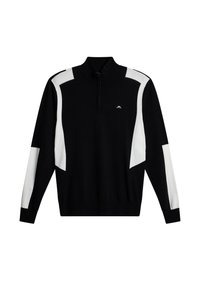 Svart stickad tröja med vita vinklade detaljer, hög krage och halvdrogkedja fram. Har en liten logotyp på bröstet. Långärmad.