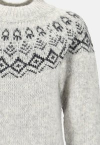 Light gray sweater with a high neckline, featuring a black Fair Isle pattern around the yoke and a soft, textured wool material.