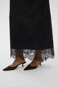 Fekete csipkeruha hullámos szegéllyel, bonyolult mintákkal díszítve. Párosítva hegyes orrú fekete mules-ekkel, rövid sarkakon.
