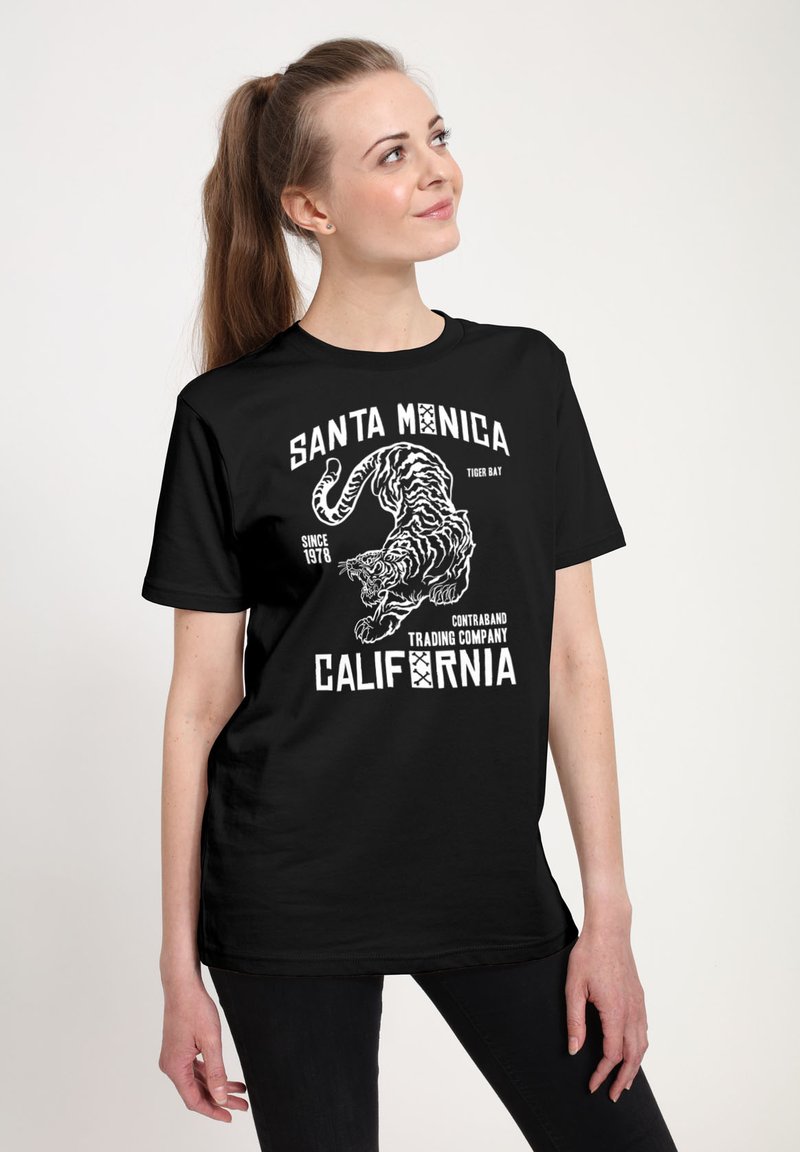 Camiseta negra con estampado gráfico blanco de un tigre, texto "Santa Monica Tiger Bat," "Contraband Trading Company," y "California."