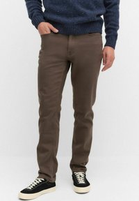 Bruna bomullsmixbyxor med slim fit, med sidofickor och en jämn yta, i kombination med svarta sneakers och en marinblå tröja.