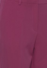 Violet housut, jotka on valmistettu sileästä kankaasta ja joissa on vartalonmyötäinen leikkaus. Niissä on etutasku ja siistit linjat, jotka tarjoavat virtaviivaisen siluetin.