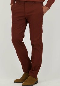 Bordeaux kleurige broek van gestructureerde stof, met een slim fit, zijkanten zakken en een knoopsluiting, gecombineerd met bruin suède enkellaarzen.