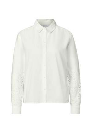 Camisa blanca de botonadura con cuello, con mangas largas y detalles de ojales intrincados en las mangas. Fabricada en una tela ligera.