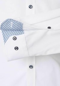 Witte button-up shirt met een contrasterende blauwe geometrische patroon manchetten. Bevat donkere knopen en heeft een gladde, frisse textuur.