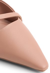 Vaaleanpunaiset, kärjellään terävät kengät, jotka on valmistettu teksturoidusta nahasta ja joissa on ristiin menevät hihnat päällyksessä. Sileä pinta, jossa on minimaalista korostusta.