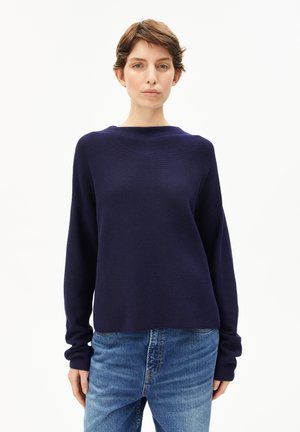 Dunkelblauer Strickpullover mit Rundhalsausschnitt, langen Ärmeln und lässiger Passform, kombiniert mit klassischen blauen Jeans.