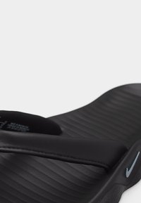 Μαύρο σανδάλι Nike slide με υφή στην επιφάνεια ποδιού και επενδυμένο λουρί, λοξή όψη που αναδεικνύει το λογότυπο στο πλάι και τις λεπτομέρειες ραφής.