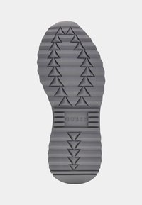 Suela de sneaker de goma gris con un patrón texturizado en zigzag y acentos triangulares. "GUESS" grabado en el centro.