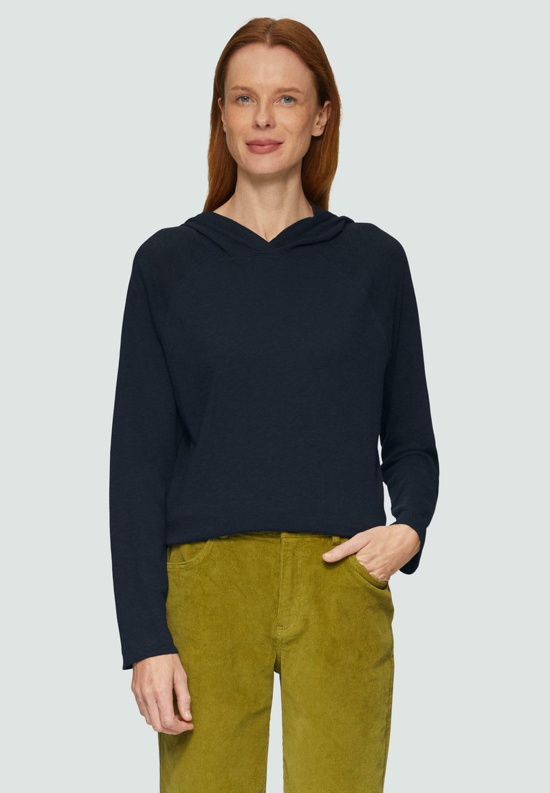 Marineblauer Kapuzenpullover mit langen Ärmeln und lässiger Passform, kombiniert mit olivgrünen Cordhosen mit Fronttaschen.