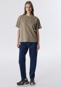 Beige katoenen t-shirt met korte mouwen, relaxed fit. Draag het met blauwe denim broek en donkere sneakers met structuur en veters.