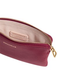 Portafoglio in pelle bordeaux con finitura testurizzata, cerniera dorata e etichetta interna che riporta "Coccinelle, Pelle Italiana Autentica."