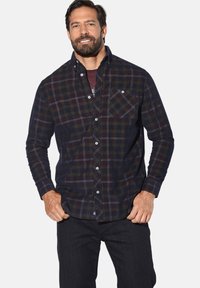 Langarmhemd im Karo-Design in Dunkelblau und Grün, mit Button-Down-Kragen, einer Brusttasche und weißen Ziernähten.