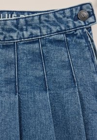 Farmernadrág szoknya pliszírozott dizájnnal, világos-közepes kék színben, gombos záródással és márkás deréktáji címkével.