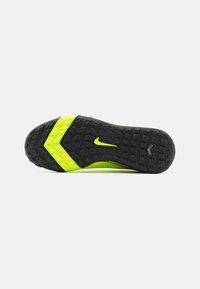 Chaussures Nike avec une semelle en caoutchouc noir, présentant un design en zigzag. Des accents jaunes vifs rehaussent la semelle intermédiaire. Surface texturée pour une meilleure adhérence.