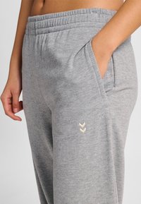 Szare bawełniane spodnie dresowe z elastycznym pasem, bocznymi kieszeniami oraz ozdobnym kremowym szwem w kształcie jodełki przy mankiecie.