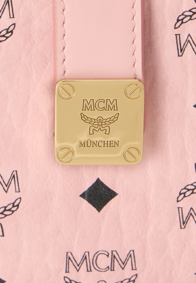 Plaque métallique carrée dorée avec logo MCM München sur un fond en cuir rose avec texte MCM noir et motifs en losange.