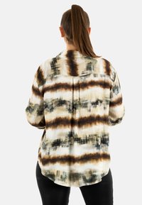 Camicia button-up con un motivo astratto in crema, marrone e verde. Tessuto leggero, maniche lunghe e orlo curvo.