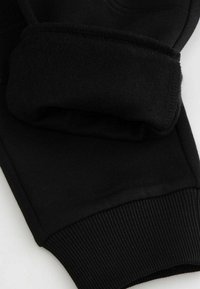 Czarny sportowy sweter z miękkim, polarowym wykończeniem mankietów i prążkowanym dołem. Gładki materiał z minimalnymi detalami szwów.