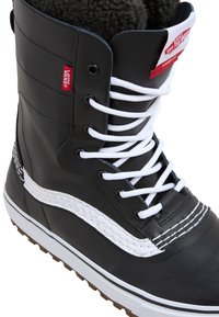 Black leather boot featuring white laces, fur lining, and white stitching. Rubber sole with textured grip patterns and Vans branding on the tongue.