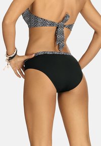 Czarny bikini z wzorzystym stanikiem typu bandeau, z wiązaniem z tyłu. Dół ma jednolity czarny design, z kontrastującymi, wzorzystymi akcentami.