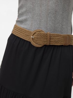 Ceinture tressée marron avec boucle ronde portée sur une jupe noire et un haut en maille grise avec un motif ajouré vertical.