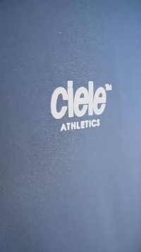Camisola atlética azul com logótipo branco bordado com o texto "ciele" e "ATHLETICS", textura de tecido suave, vista em plano aproximado.
