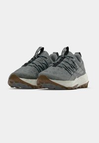 Graue Schuhe für den Außenbereich mit einem Obermaterial aus strukturiertem Stoff, Schnürdesign und Gummisohlen mit einem dreieckigen Profil. Schwarzer Ziehhilfe an der Ferse.