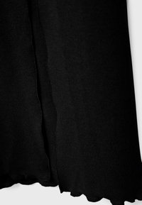 Tissu côtelé noir avec une finition texturée et des bords festonnés. Le matériau est doux et flexible, présentant des lignes verticales dans le tissage.