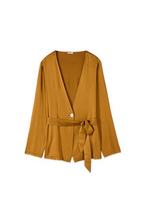 Long-sleeve mustard yellow blouse with deep V-neck, single white button closure, and matching fabric belt tied at the waist.