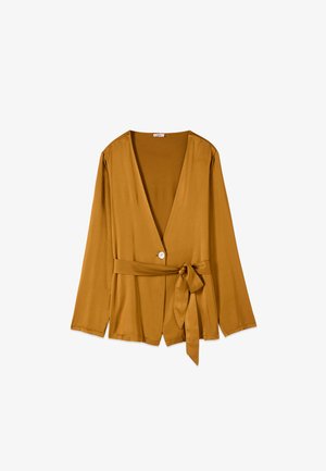 Long-sleeve mustard yellow blouse with deep V-neck, single white button closure, and matching fabric belt tied at the waist.