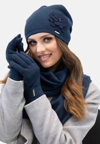 Marineblaue Strickmütze mit einem Filzblumenakzent, passenden Handschuhen und einem Schal aus strukturiertem Stoff. Das Set enthält ein silbernes Hardware-Detail.