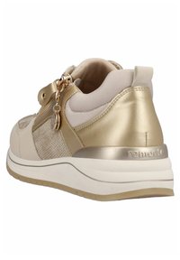Sneaker beige e oro con una parte superiore testurizzata, accenti dorati, chiusura con zip e una suola bianca spessa con un battistrada marrone chiaro.