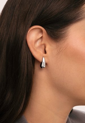 Boucles d'oreilles en argent en forme de goutte d'eau avec une finition polie, présentant une surface lisse et des détails subtils près du sommet.