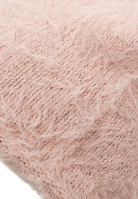Texturerad rosa stickad tyg med mjuk, fluffig yta och lösa trådar, som visar upp ett mysigt, lätt material och sammanflätade mönster.