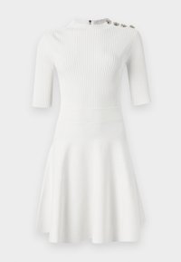 Vestido blanco de canalé con mangas cortas, cuello alto, cuerpo ajustado, falda acampanada y tres botones decorativos en un hombro. Textura suave.