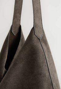 Geantă tote din suede gri, cu curele plate pentru umăr, având o textură netedă și un detaliu subtil de cusătură pe margini.