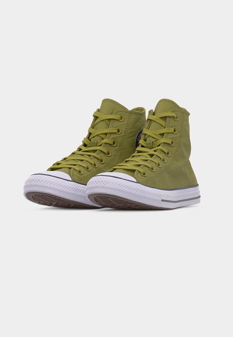 Par de zapatillas de lona de caña alta en verde oliva con suelas y punteras de goma blanca, con cordones y un parche de logo circular en el lateral.