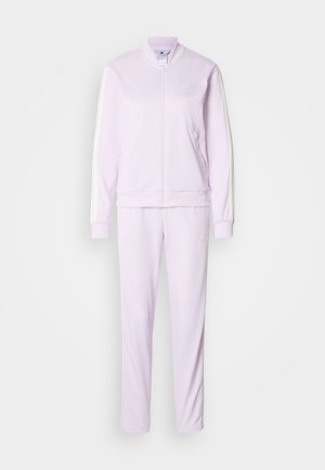 Survêtement violet clair comprenant une veste zippée et un pantalon assorti, fabriqué en tissu lisse avec des bandes blanches sur les côtés et un logo en accent.