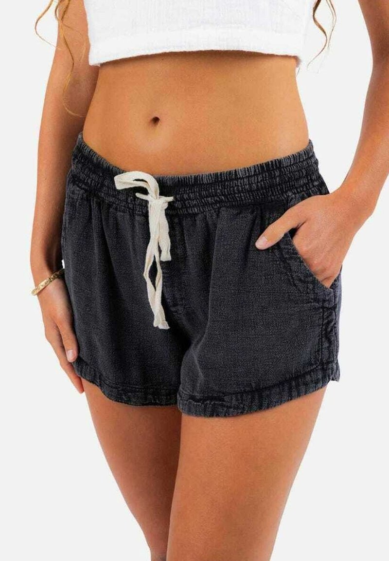 Shorts en coton noir avec une taille élastique, un cordon de serrage et des poches latérales. Le tissu a une apparence texturée.