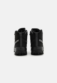 Czarne buty trekkingowe z wysoką cholewką, teksturowaną górą, wyściełanym kołnierzem i agresywnym wzorem bieżnika na podeszwie dla lepszej przyczepności.