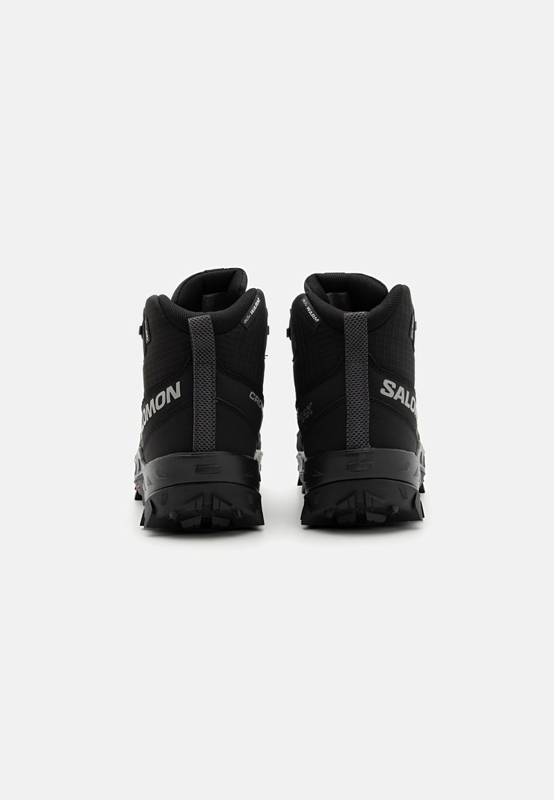 Scarpe da trekking nere con design a caviglia alta, parte superiore testurizzata, collo imbottito e un modello di battistrada aggressivo sulla suola per una maggiore aderenza.