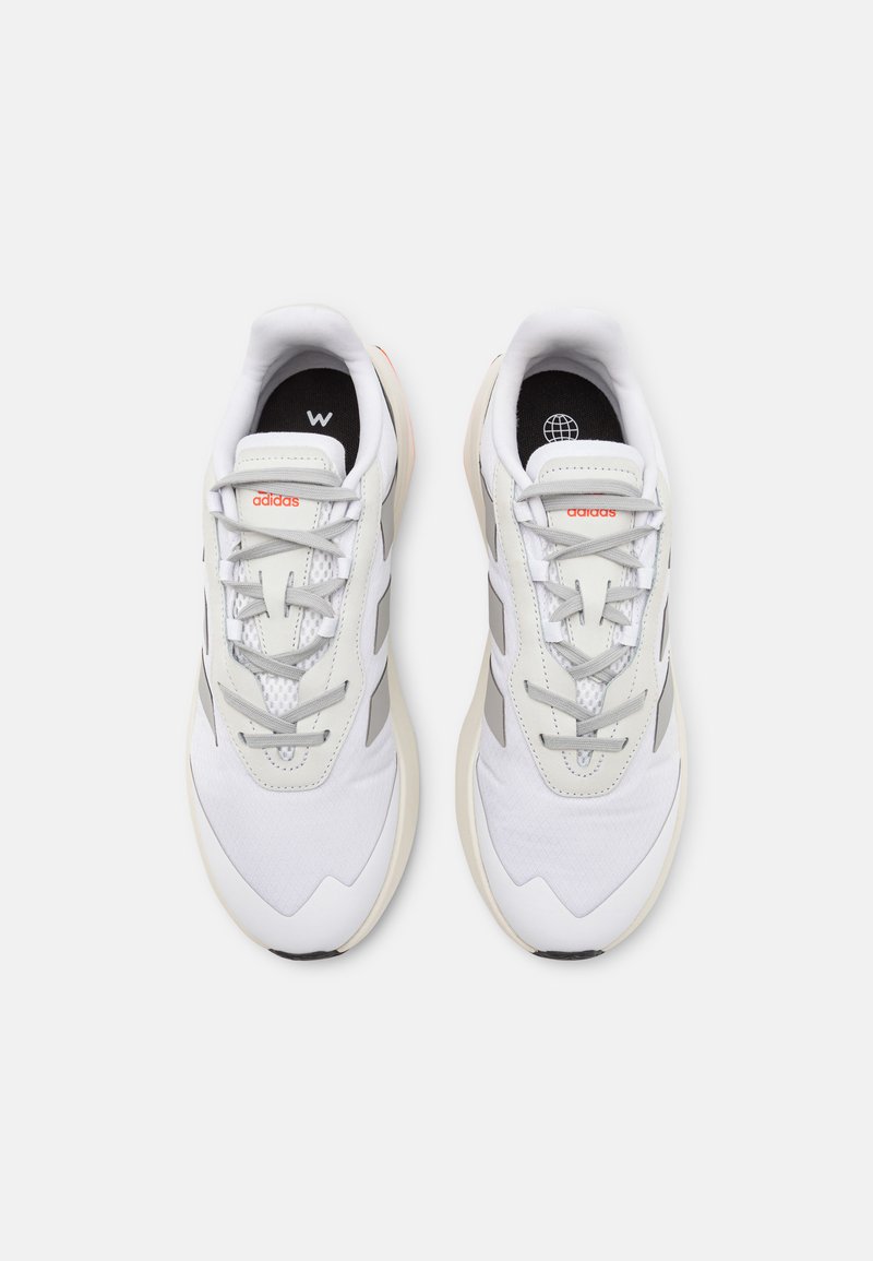 Sneakers sportivi bianchi con accenti grigi, pannelli in rete e superfici testurizzate. Dotati di un design con lacci e un colletto imbottito per il comfort.