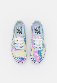Multifargede tie-dye lerretssko i blått, gult og rosa med hvite lisser og en svart gummisåle, med et prikkete innerfôr.