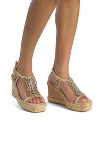 Sandali con tacco a cuneo beige che presentano un design T-strap con perline intricate, un tacco avvolto in juta e una texture morbida simile alla suede.