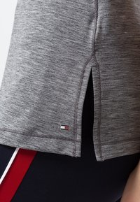 Grijs atletisch T-shirt met een gemêleerde textuur, zijslits en een klein merklogo nabij de zoom. Het heeft een relaxte pasvorm en duurzame stiksels.